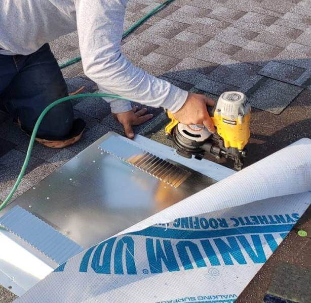 Man with nail gun shingling roof
